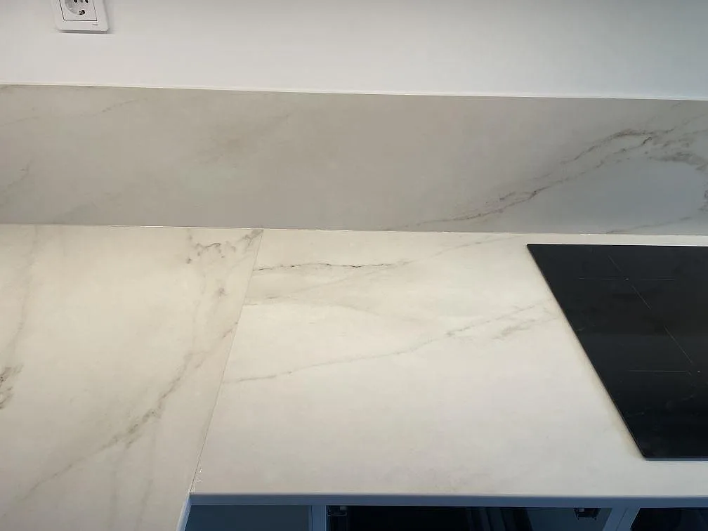 Vit Dekton Rem Velvet köksbänkskiva med induktionshäll och marmorlik ådring, matt finish, i ett kök i Malmö.