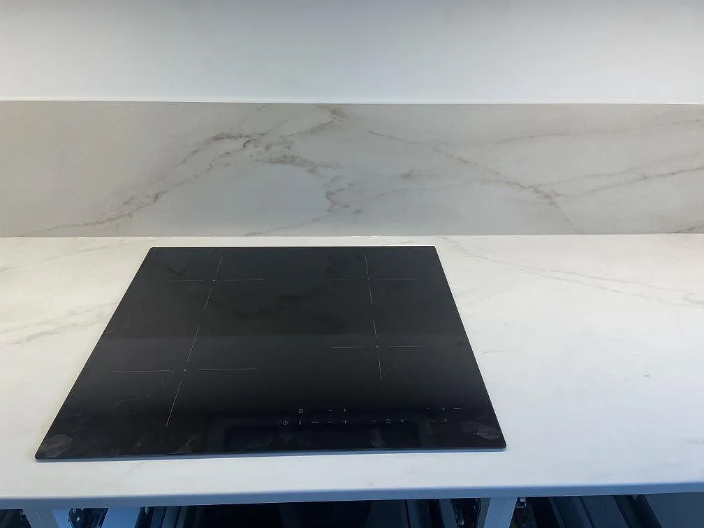 Matt köksbänkskiva i Dekton Rem Velvet med infälld svart induktionshäll och heltäckande stänkskydd i samma sten i ett kök i Malmö.