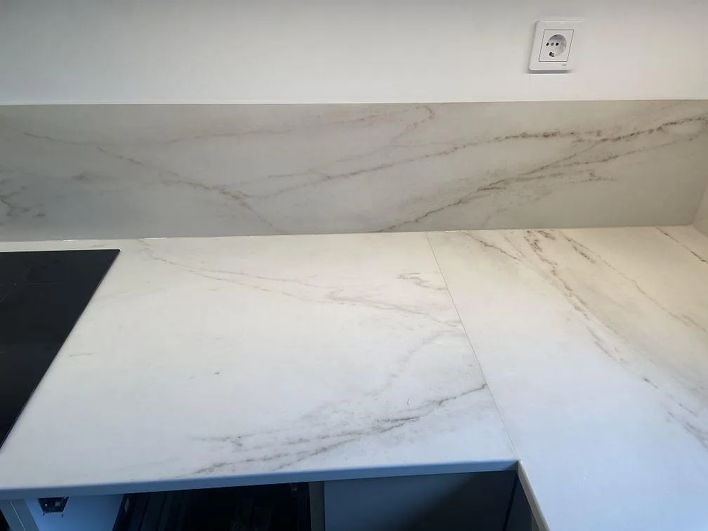 Köksbänkskiva i matt Dekton Rem Velvet med induktionshäll och fondvägg i samma sten i ett kök i Malmö.