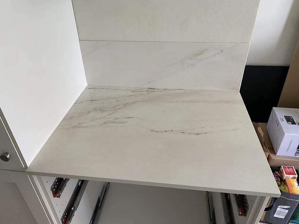 Avslutande bänkdel i matt Dekton Rem Velvet keramik med tydlig ådring och stänkskydd under montering i Malmö.