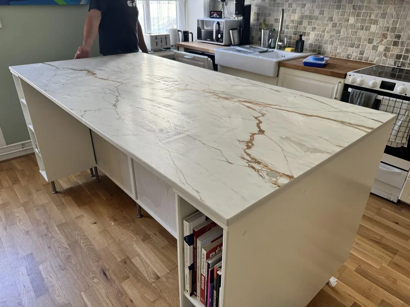 Installerad köksö i matt Dekton Reverie med lång bänkskiva och synlig marmorerad ådring under montering i Malmö.