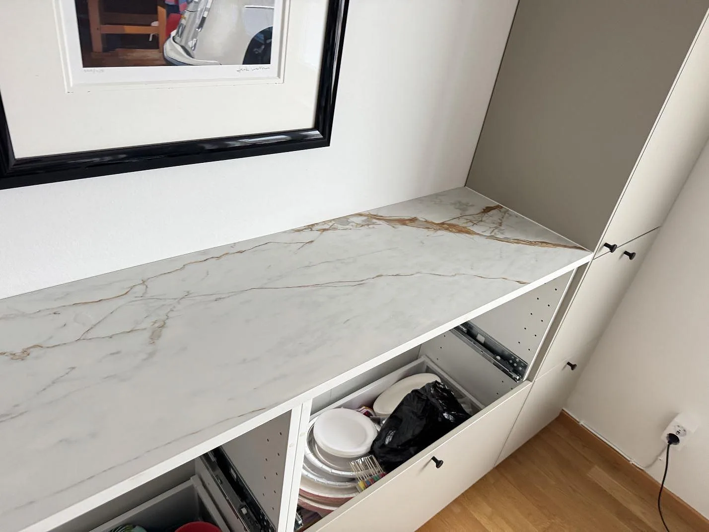 Lång köksbänkskiva i matt Dekton Reverie på vita köksstommar med tydlig ådring i Oxie.