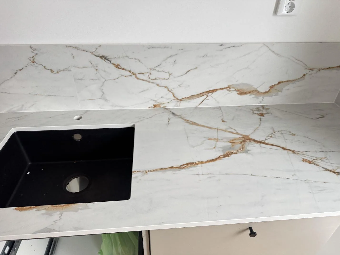 Dekton Reverie i matt keramik med ljus botten, varm ådring och svart diskho vid stänkskyddet i Oxie.