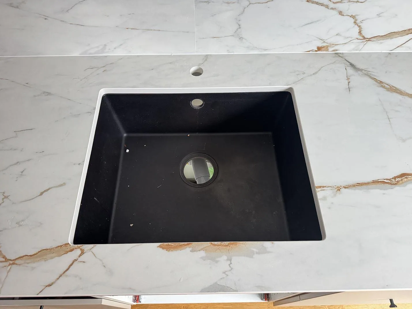 Närbild av svart diskho i en matt Dekton Reverie köksbänkskiva med matchande stänkskydd i Oxie.