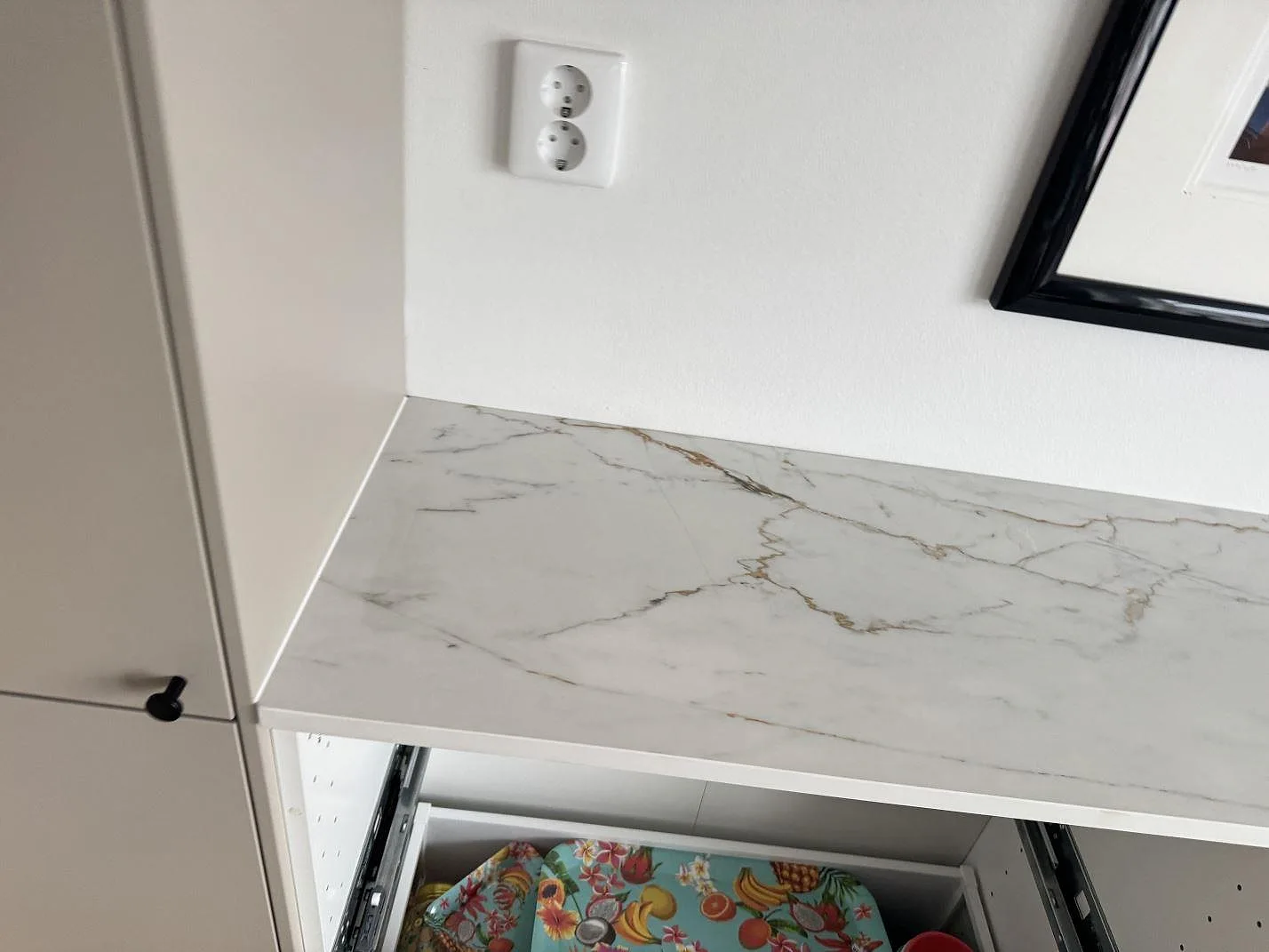 Detalj av matt Dekton Reverie som köksbänkskiva under vägguttag och tavla i ett kök i Oxie.