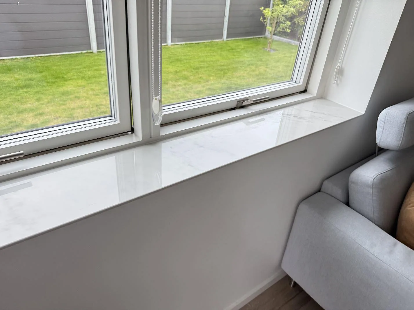 Lång fönsterbänk i polerad Dekton Salina keramik under dubbla fönster i Ishøj.