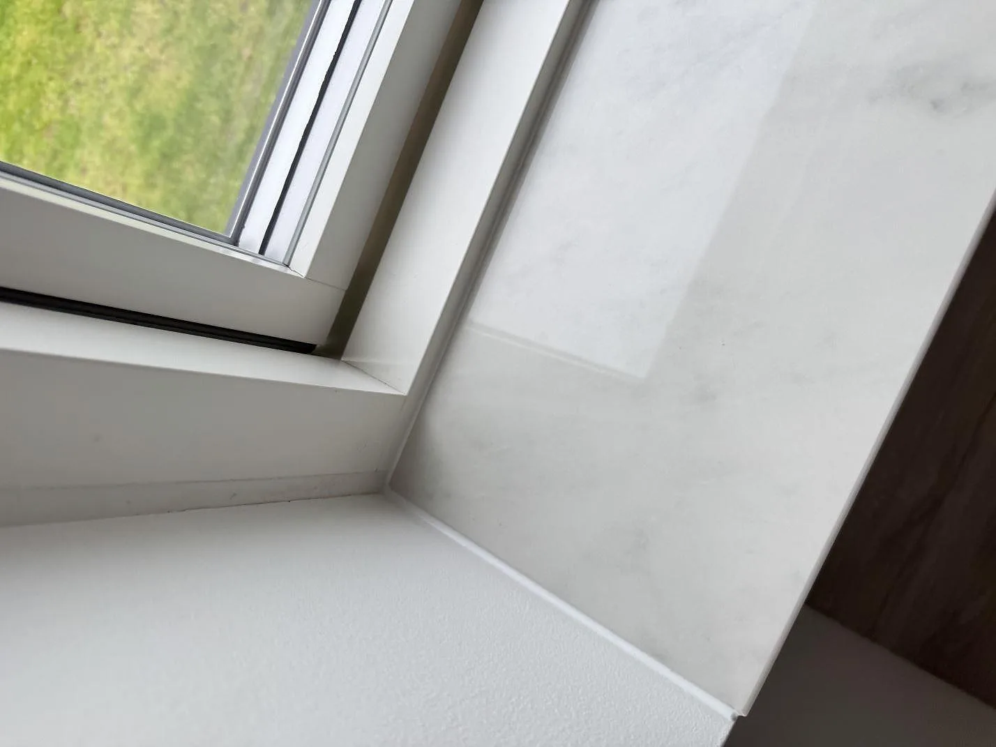 Detalj av polerad Dekton Salina fönsterbänk i keramik vid fönsternisch i Ishøj.