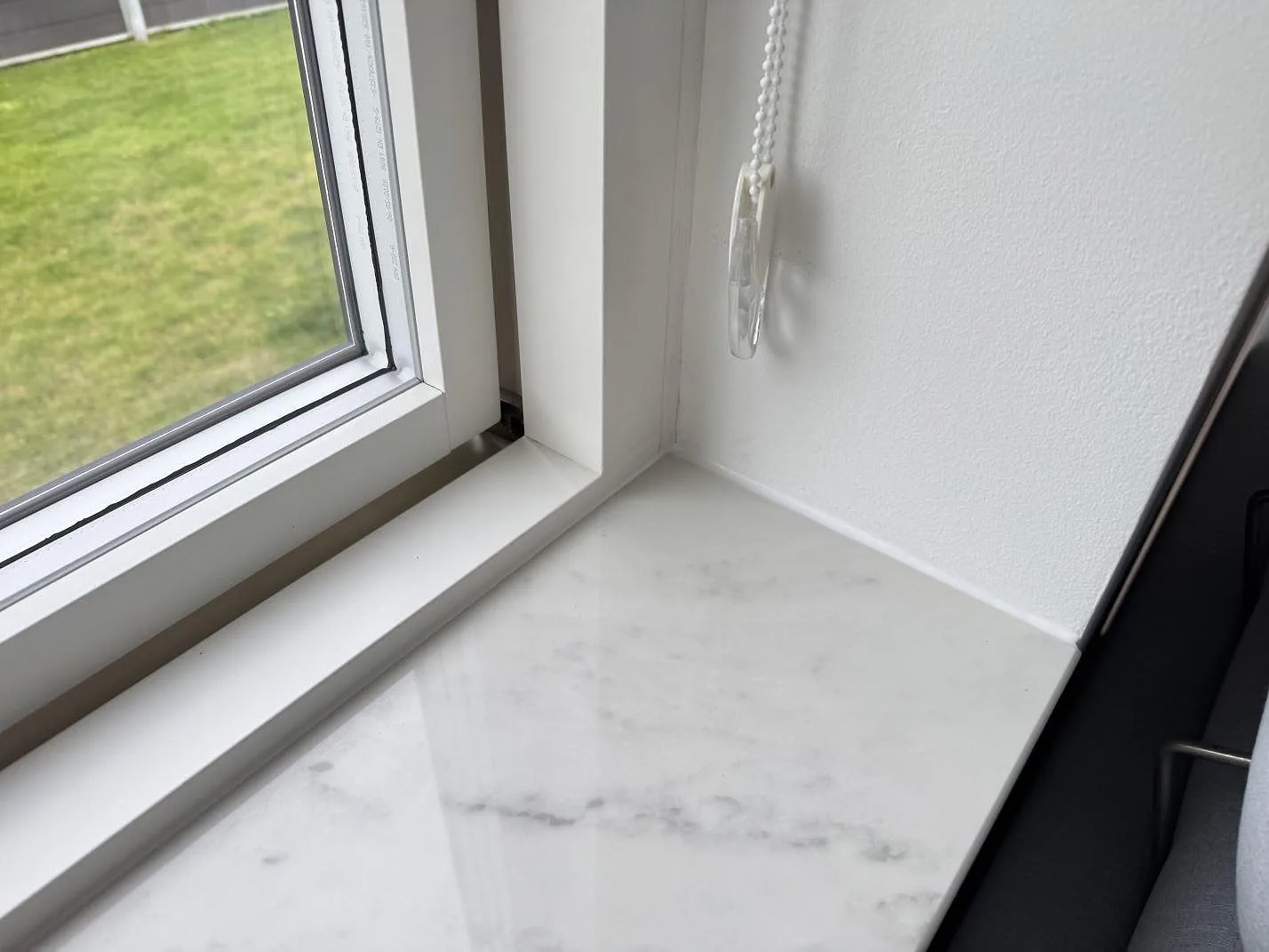 Närbild av fönsterbänk i polerad Dekton Salina keramik med fönsterhörn i Ishøj.