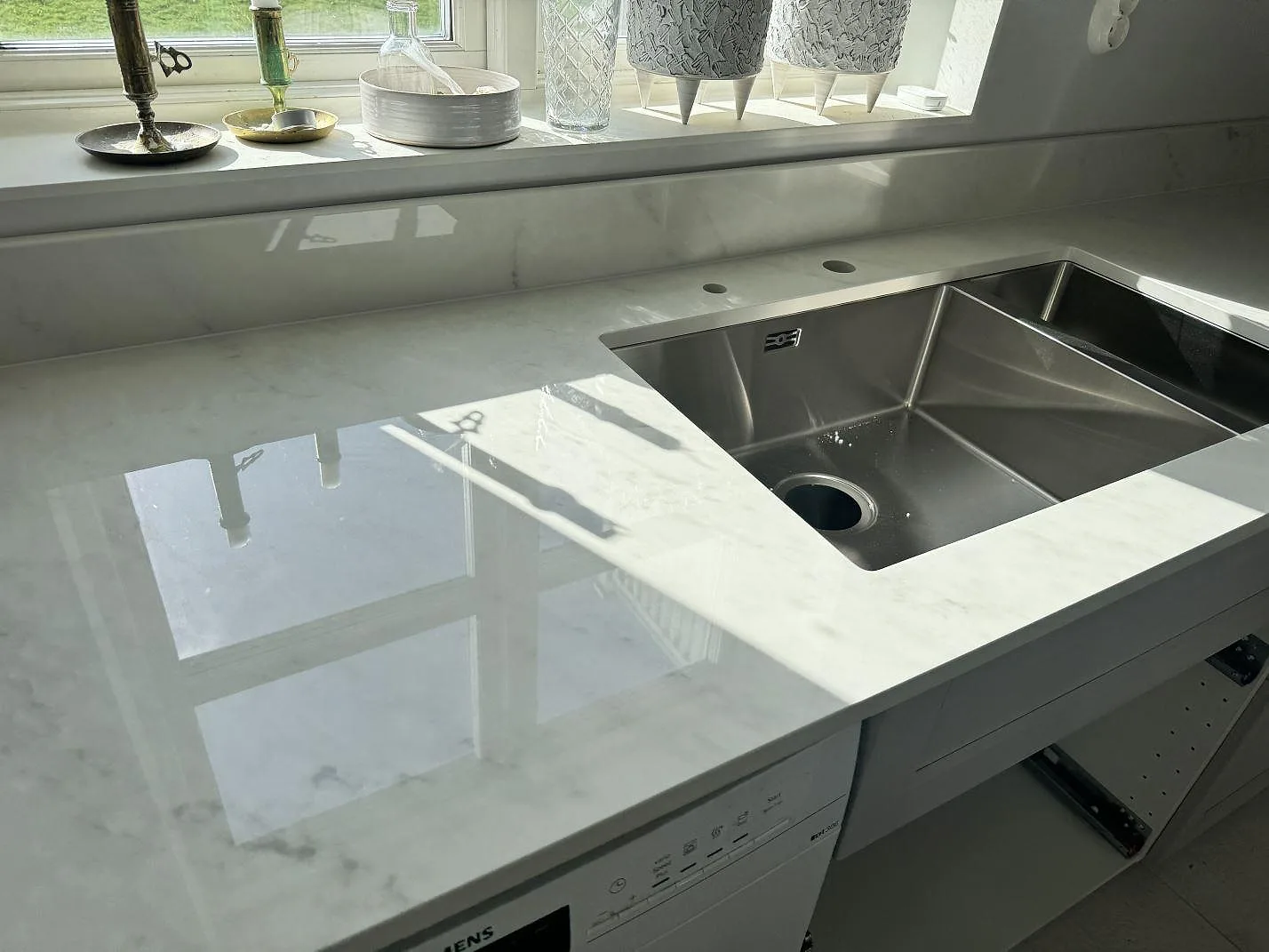 Köksbänkskiva i polerad Dekton Salina keramik, 20 mm, med underlimmad dubbel rostfri diskho och fönsterljus i Sävedalen.