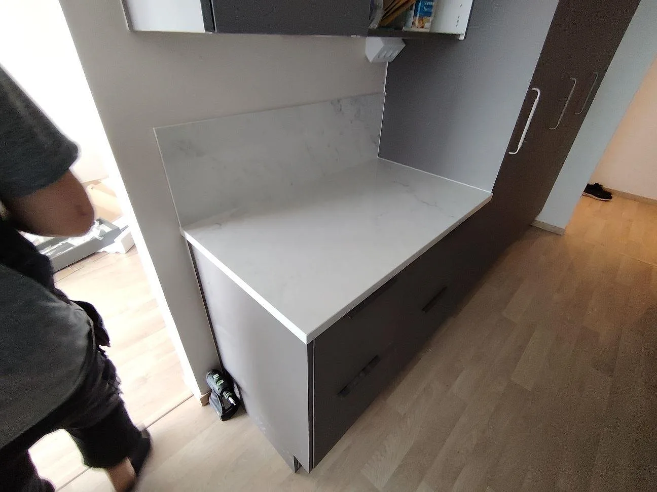 Sidovy av ljus köksbänkskiva i polerad Dekton Salina med uppvikt stänkskydd och synlig ådring i Stockholm.