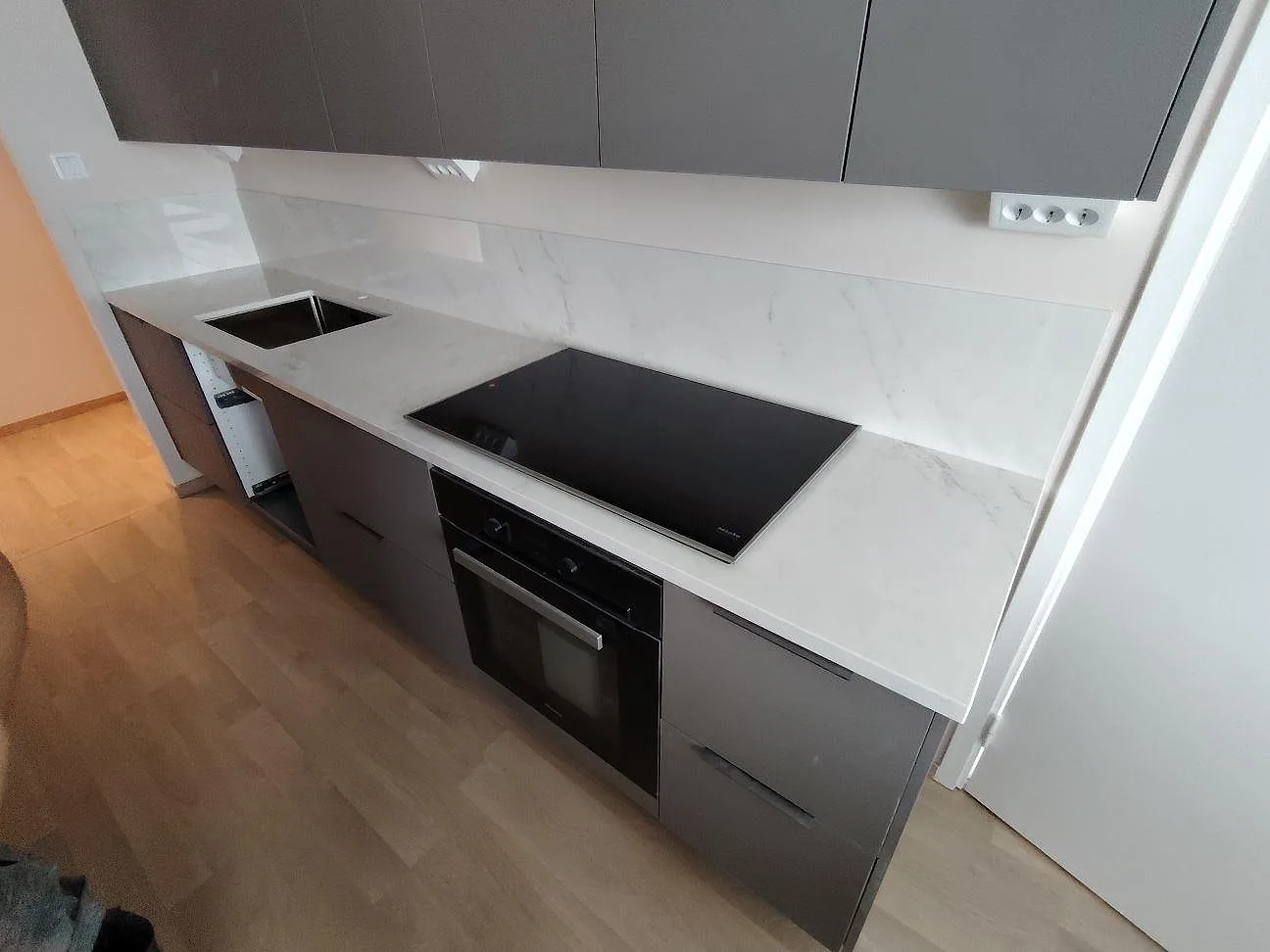 Närbild på polerad Dekton Salina som köksbänkskiva och stänkskydd med häll och diskho i Stockholm.