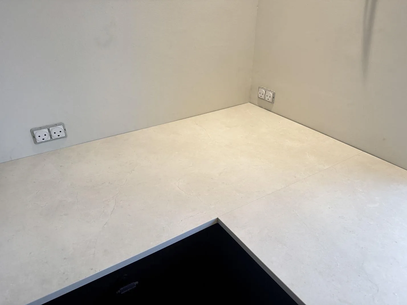 Hörndel av L-formad köksbänkskiva i matt Dekton Sandik över mörka köksstommar i Kgs Lyngby.