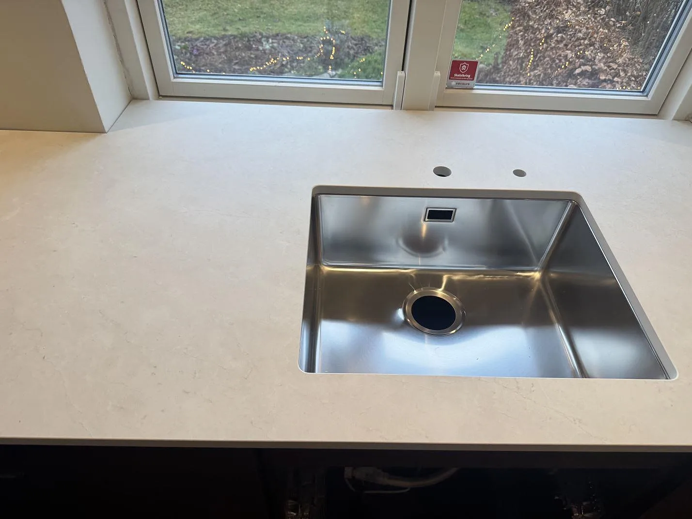 Rostfri diskho i en matt Dekton Sandik köksbänkskiva, monterad vid fönstret i ett kök i Kgs Lyngby.
