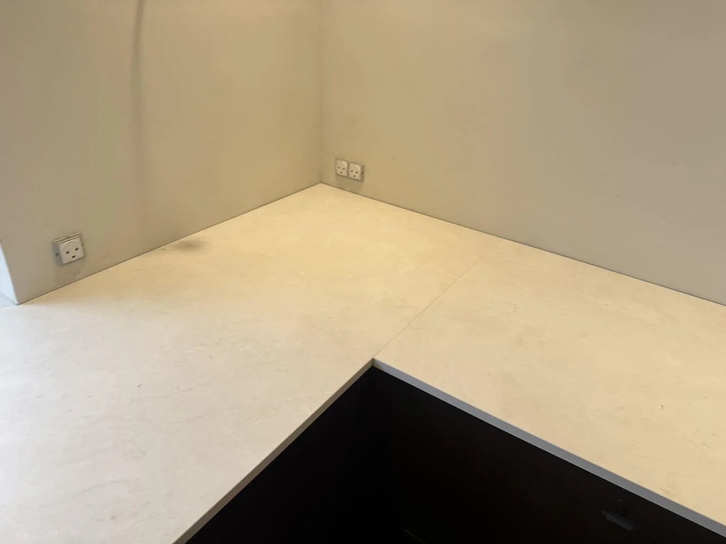 Närbild på den matta ljusa ytan i Dekton Sandik köksbänkskiva runt kökets hörn i Kgs Lyngby.