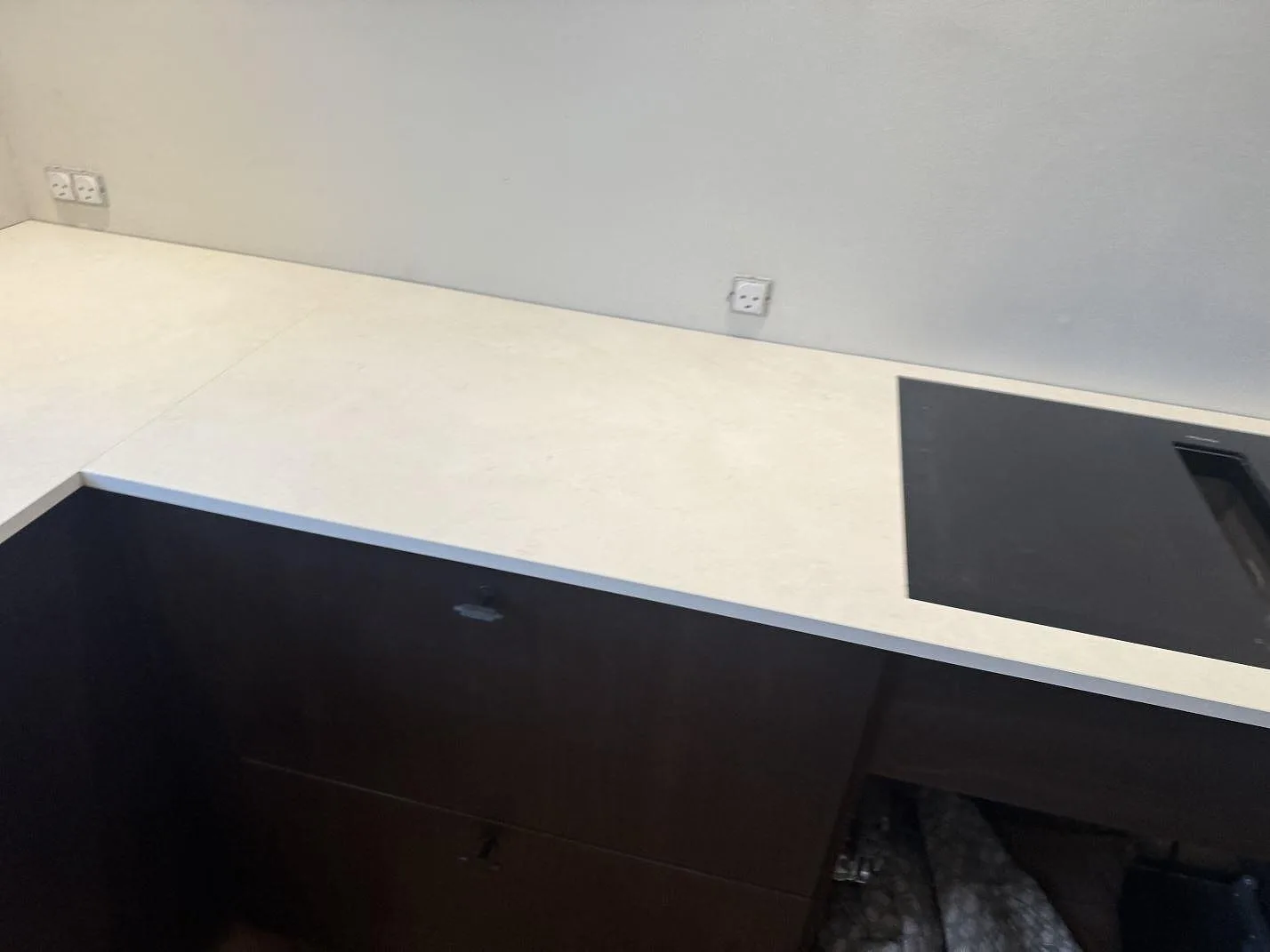 Matt köksbänkskiva i Dekton Sandik med synlig häll och lång arbetsyta över mörka köksstommar i Kgs Lyngby.