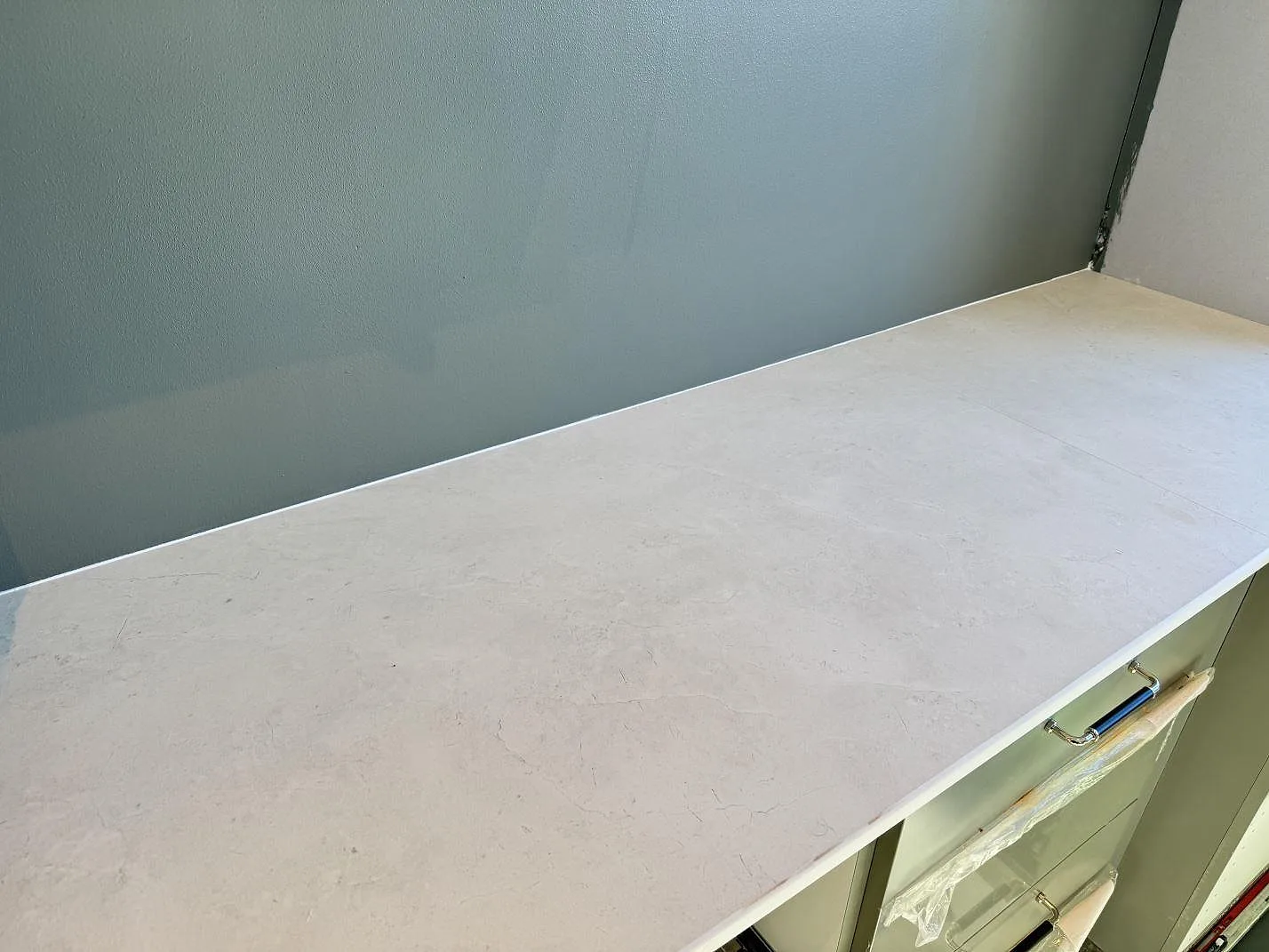 Rak köksbänkskiva i matt Dekton Sandik, ljus keramik, monterad längs vägg över köksstommar i Malmö.