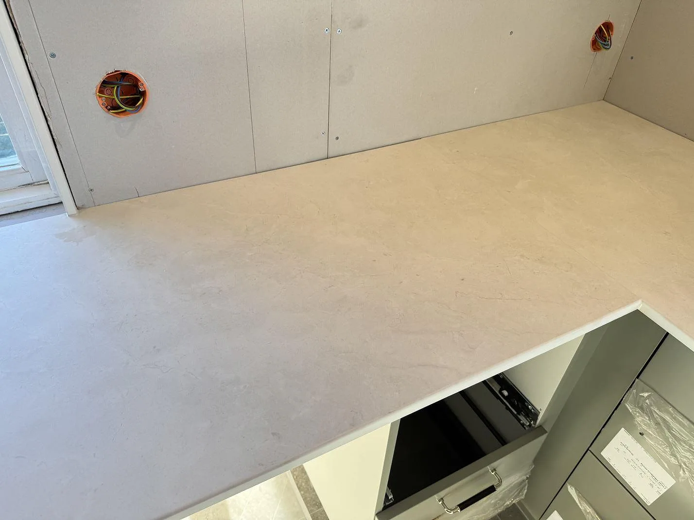 Bänkyta i matt Dekton Sandik, 20 mm keramik, över öppna köksstommar under montering i Malmö.