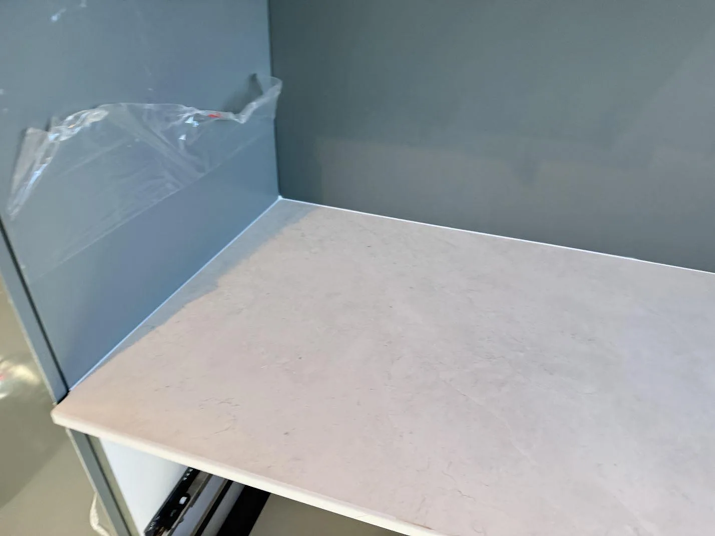 Närbild på hörn av köksbänkskiva i matt Dekton Sandik med ljus ådring och skyddsplast på väggen i Malmö.