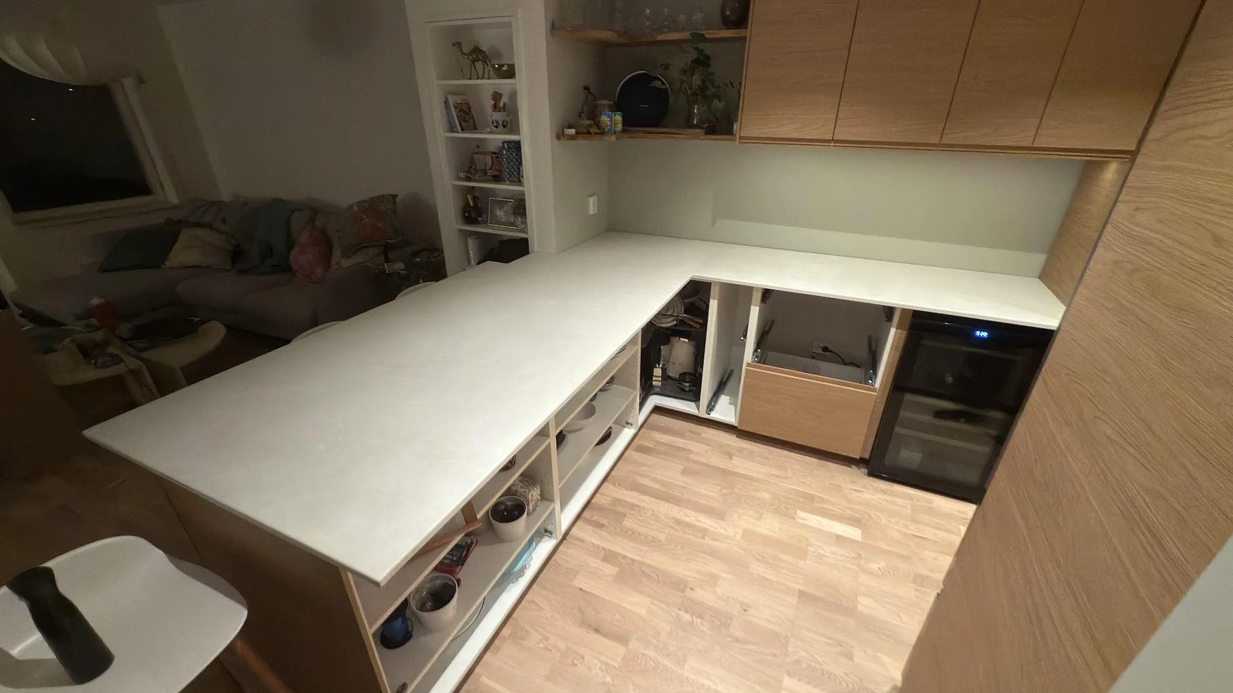 Lång köksbänk i sandfärgad Dekton Sandik som löper ut mot vardagsrummet i ett hem i Saltsjö-Boo.
