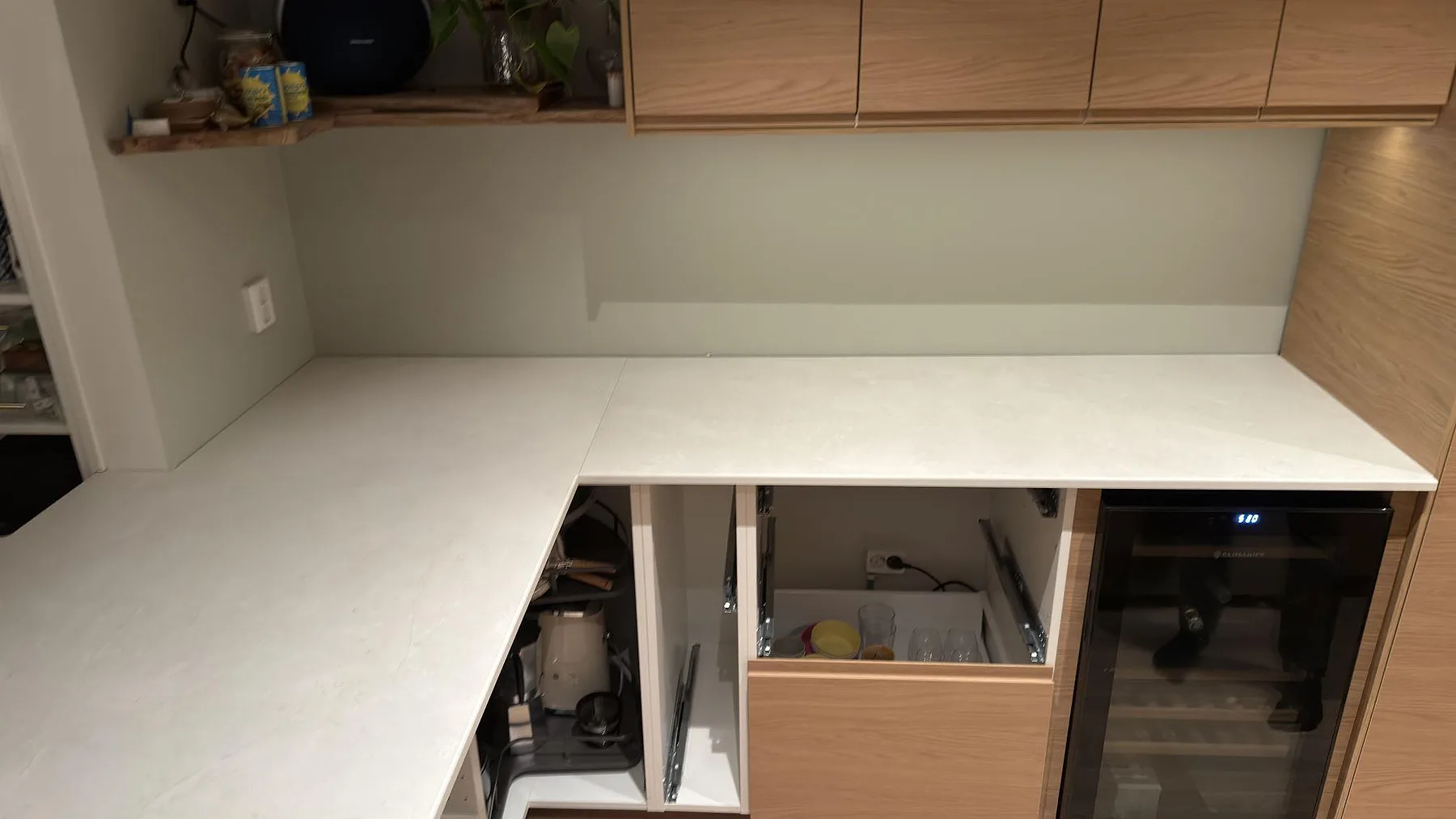 Hörnparti av köksbänk i matt Dekton Sandik med lågt stänkskydd och vinkyl under, Saltsjö-Boo.
