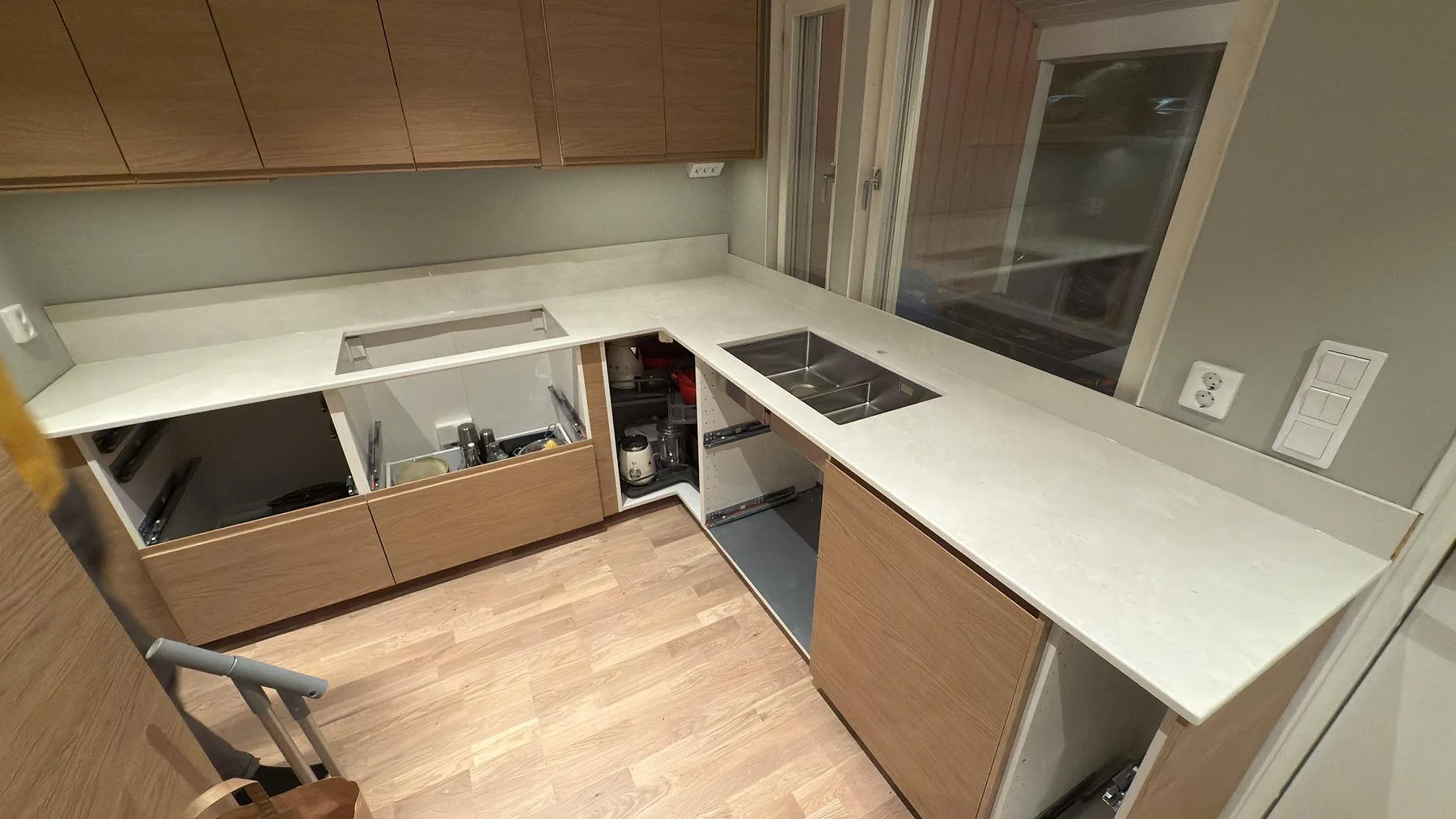 L-formad köksbänk i Dekton Sandik under montering med diskho och öppna stommar, varm sandton, Saltsjö-Boo.