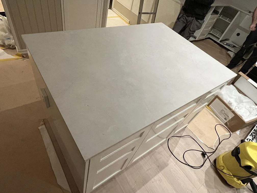 Stor arbetsyta i matt Dekton Sandik på ljusa köksstommar under montering av köksbänkskiva i Värmdö.