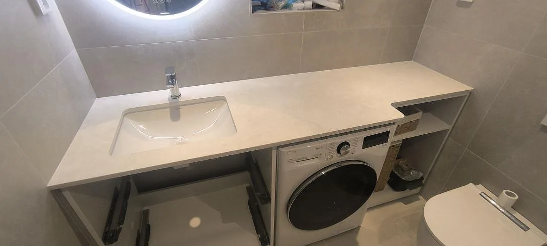 Badrumsbänkskiva i matt Dekton Sandik med tvättställ och tvättmaskin i ett badrum i Värmdö.