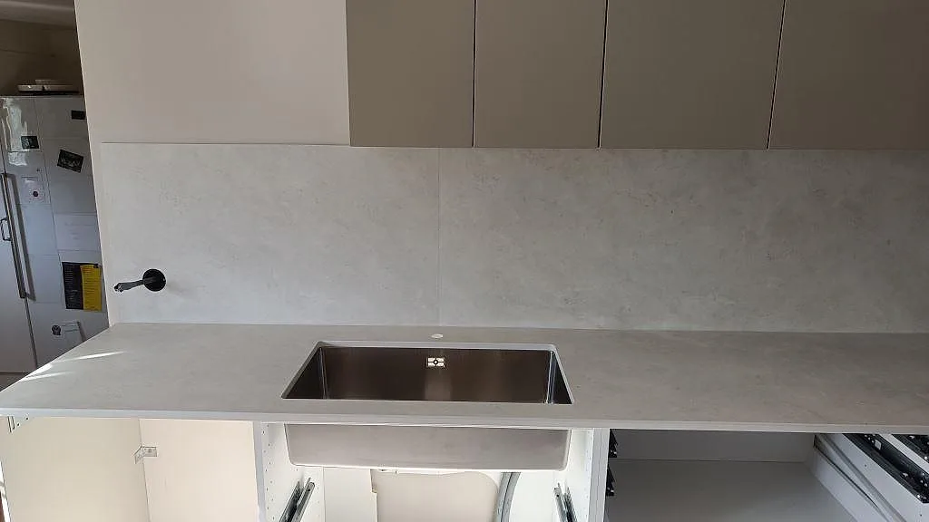 Rak vy över matt Dekton Sandik köksbänkskiva med monterad rostfri diskho och matchande stänkskydd i Vellinge.