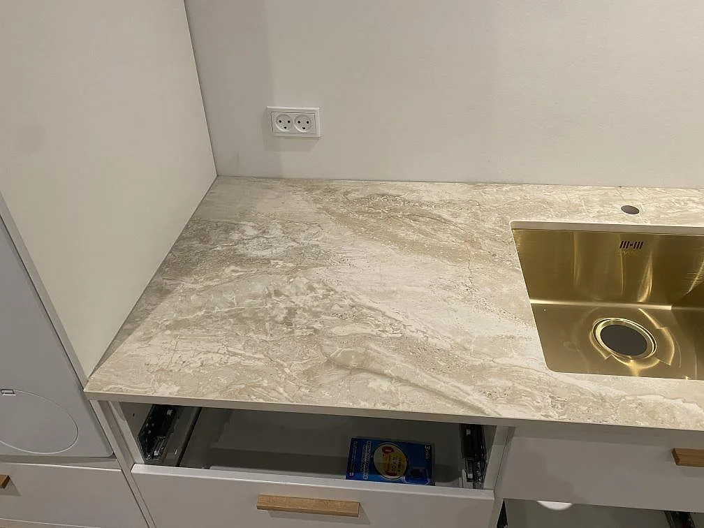 Köksbänkskiva i Dekton Sarey i Jyderup med en underlimmad borstad mässingsfärgad diskho och tydlig ljus stenådring, matt yta.