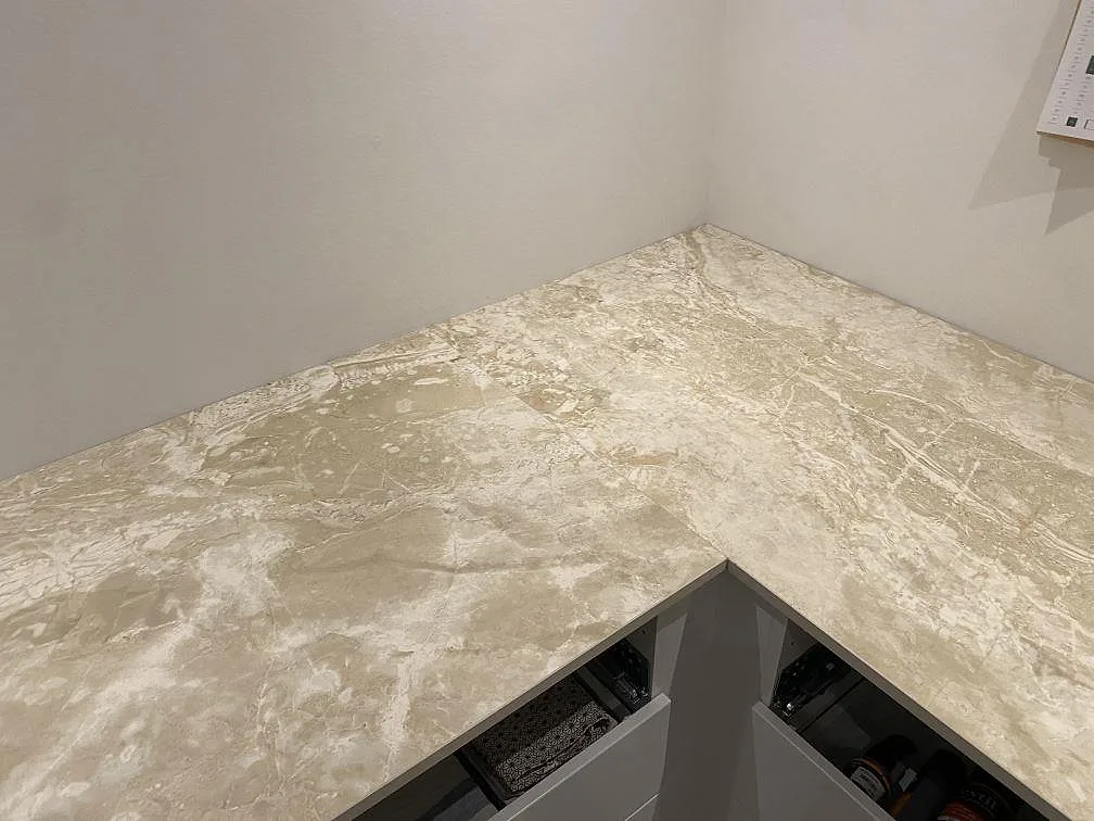 Hörnparti av en köksbänkskiva i matt Dekton Sarey i Jyderup som visar den ljusa stenens varma ådring.