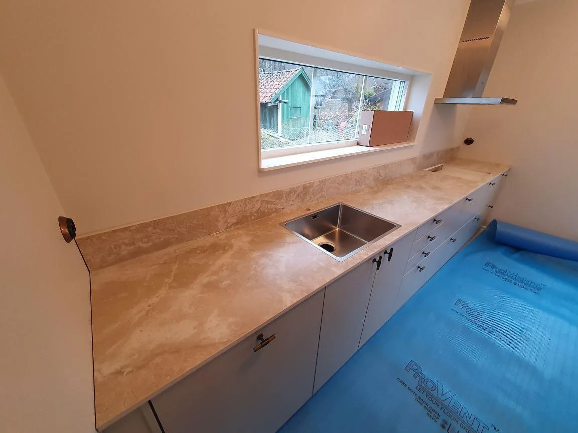 Bänkskiva i Dekton Sarey med underlimmad rostfri diskho vid fönstret i ett kök i Segeltorp.