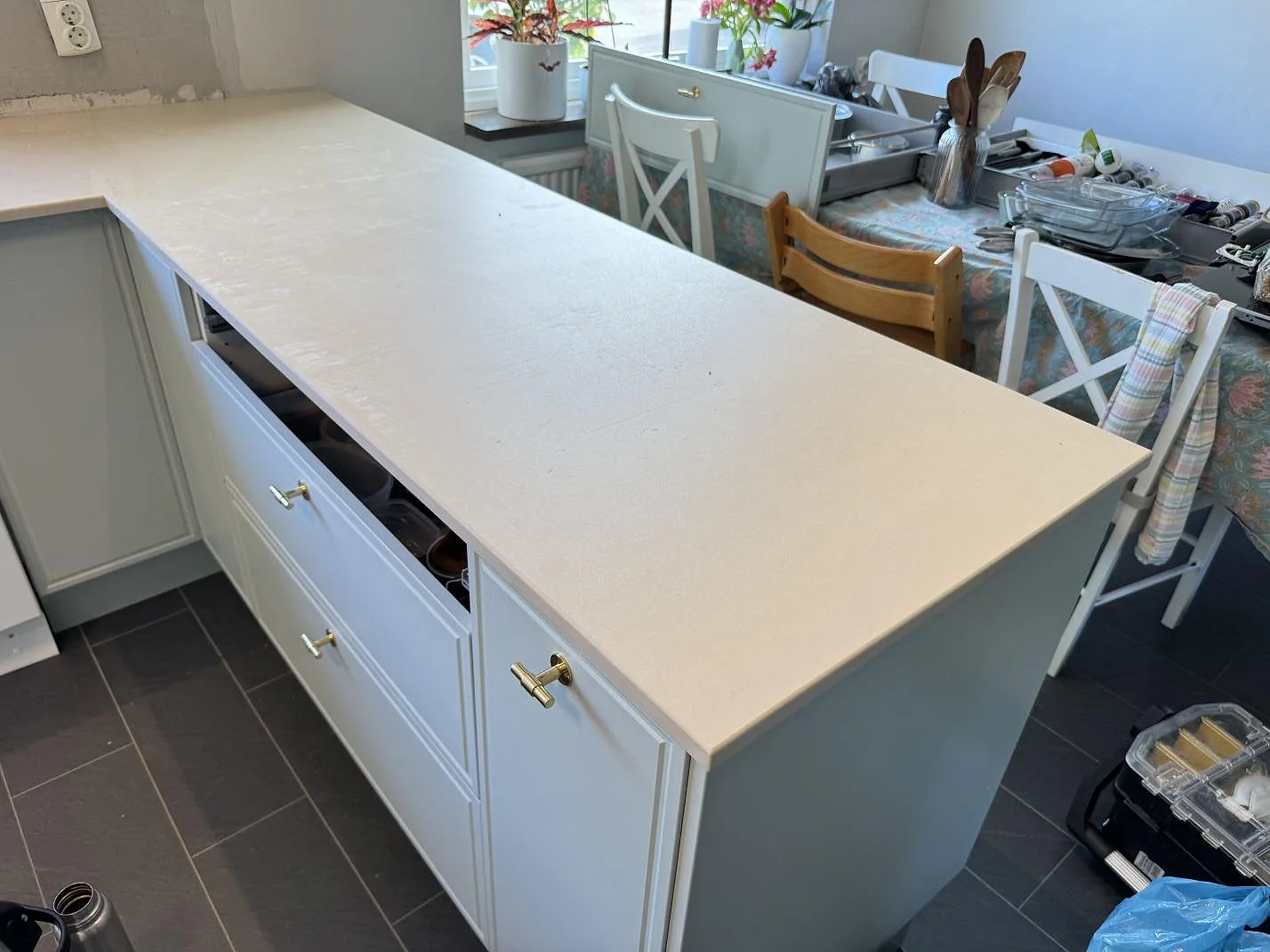 Matt köksbänkskiva i Dekton Sasea, keramik, som lång arbetsyta mot matplatsen i ett kök under montering i Åkarp.