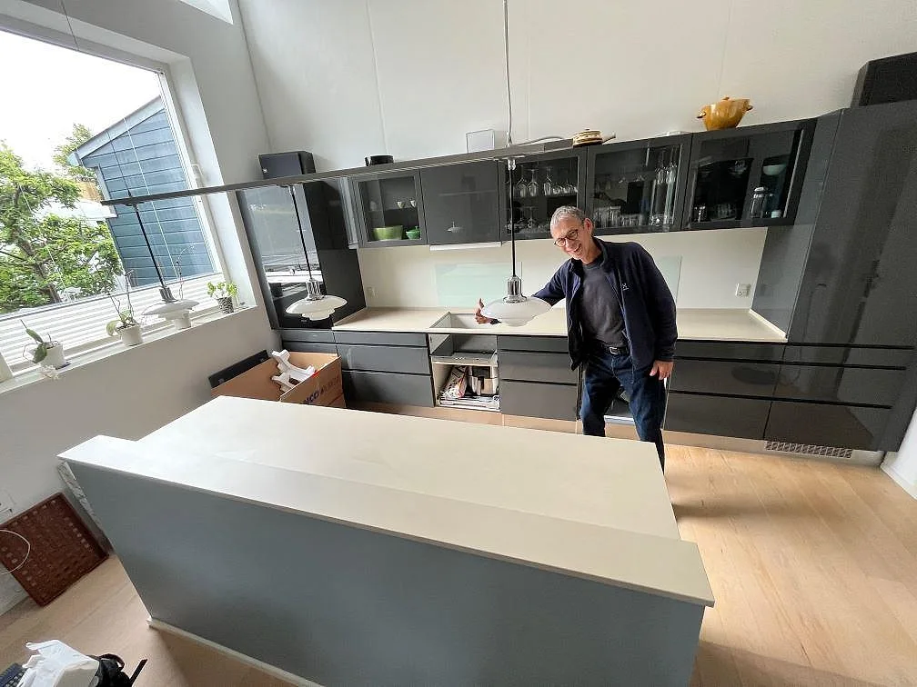 Köksbänkskiva i ljus matt Dekton Sasea med köksö och bänkstråk mot mörkgrå skåp i ett kök i Fredensborg.
