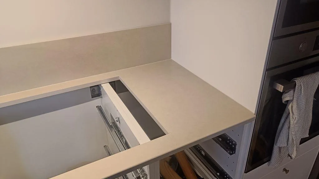 Hörndel av matt Dekton Sasea bänkskiva med urtag för häll och vit köksstomme i Malmö.