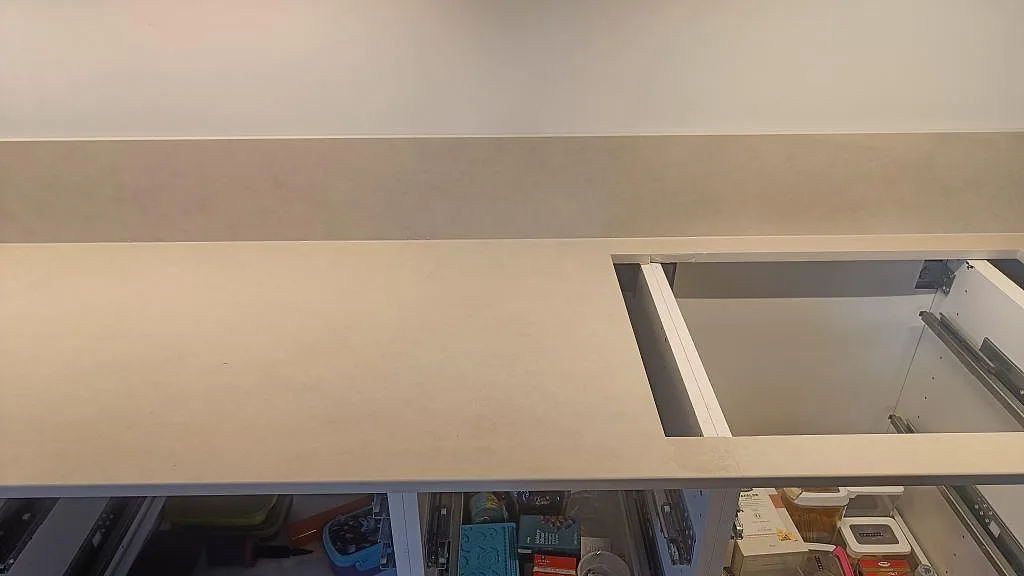 Lång arbetsyta i matt Dekton Sasea med låg stänkkant och hällurtag i ett kök i Malmö.