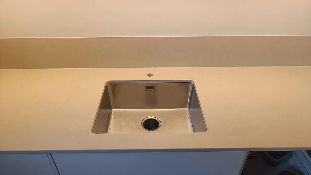 Närbild på matt Dekton Sasea bänkskiva med diskho och låg stänkkant i ett kök i Malmö.