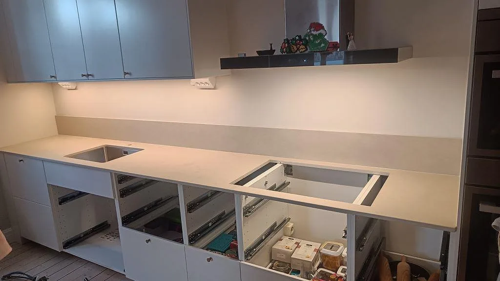 Köksbänkskiva i Dekton Sasea, matt grågrön ton, med underlimmad rostfri diskho och uppvikt stänkkant i ett kök i Malmö.