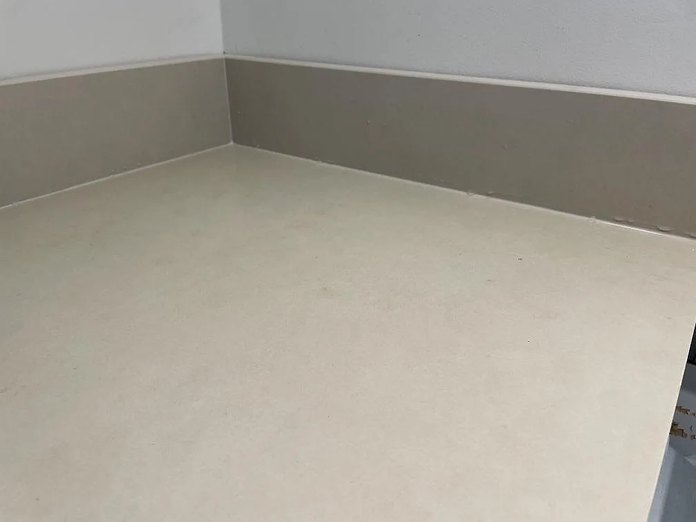 Närbild på den matta beige ytan i Dekton Sasea med uppvikt stänkkant och vägganslutning i ett kök i Malmö.