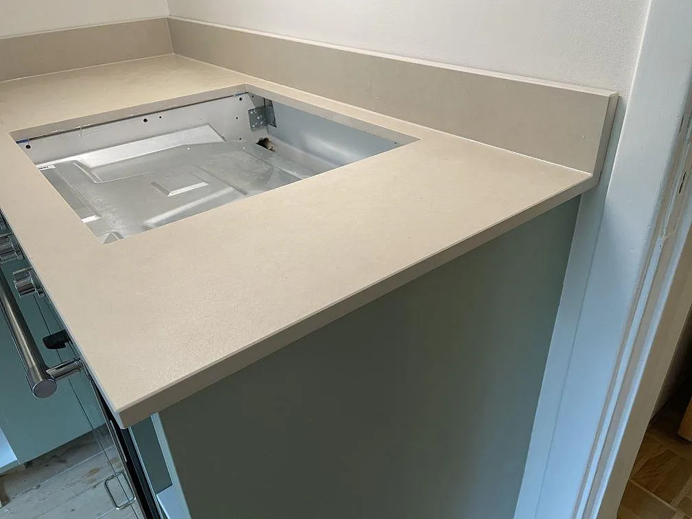 Köksbänkskiva i matt Dekton Sasea keramik i Malmö med utskärning för svart induktionshäll och uppvikt stänkkant.