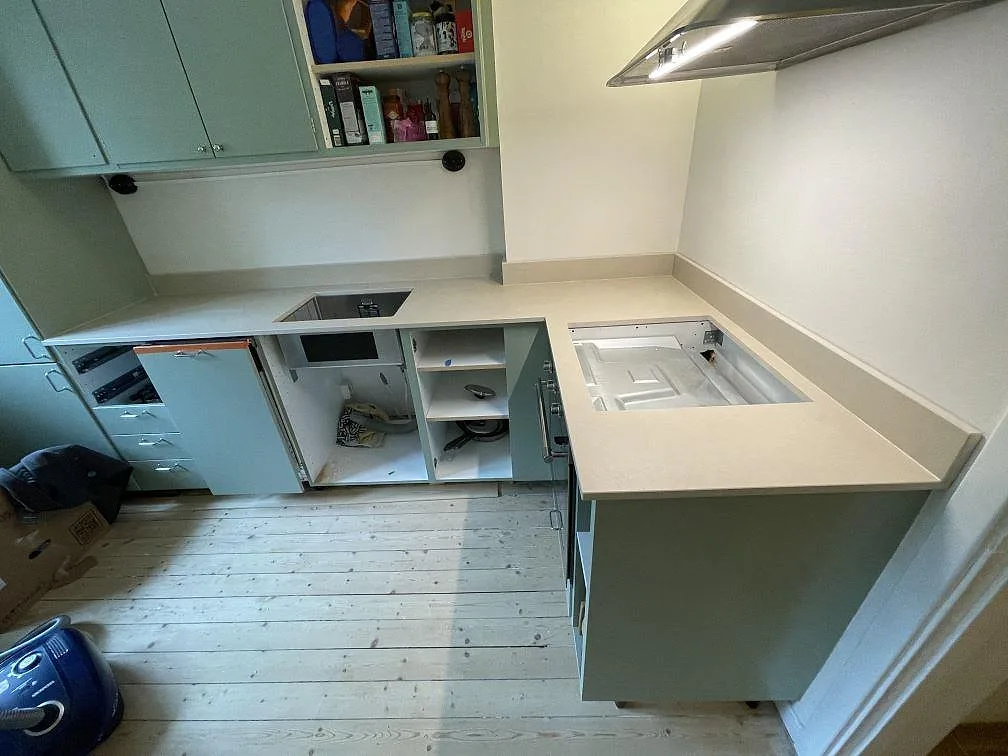 L-format kök i Malmö med 20 mm matt Dekton Sasea som köksbänkskiva, uppvikt stänkkant, underlimmad rostfri diskho och hällöppning under montering.