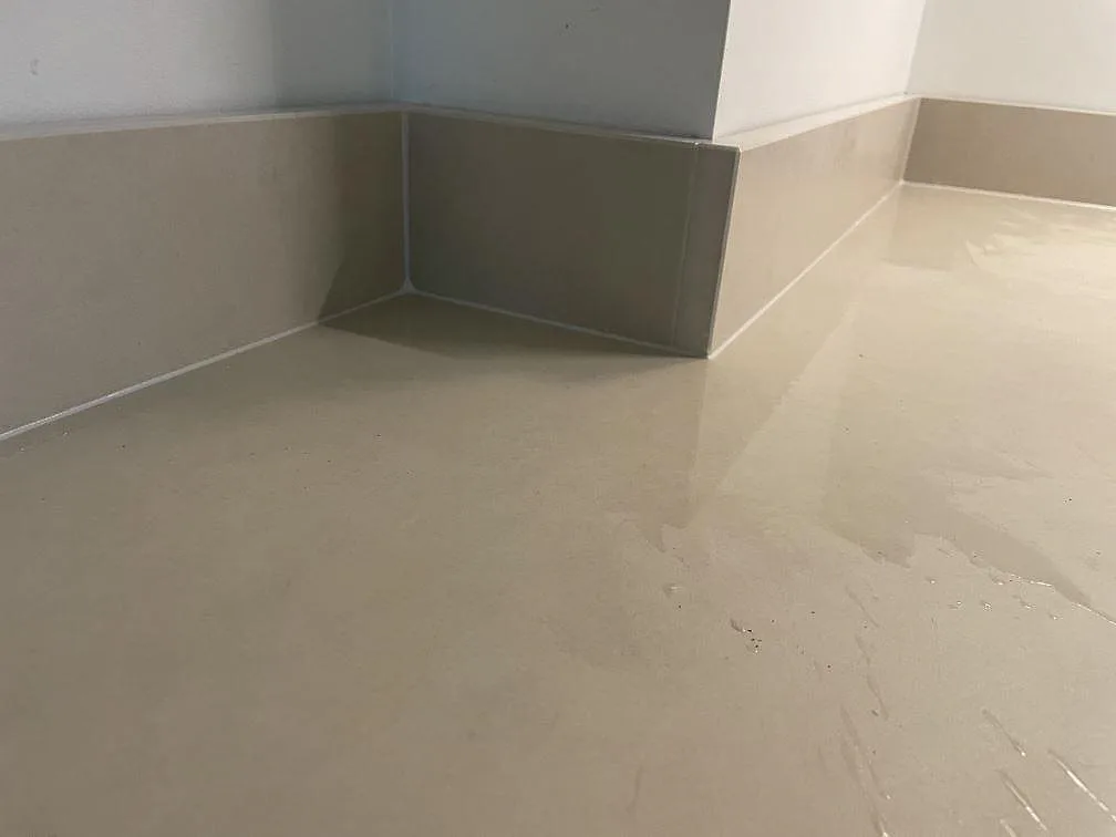 Detalj av Dekton Sasea keramik i matt finish med uppvikt stänkkant runt ett vägguttag och varm beige yta i Malmö.