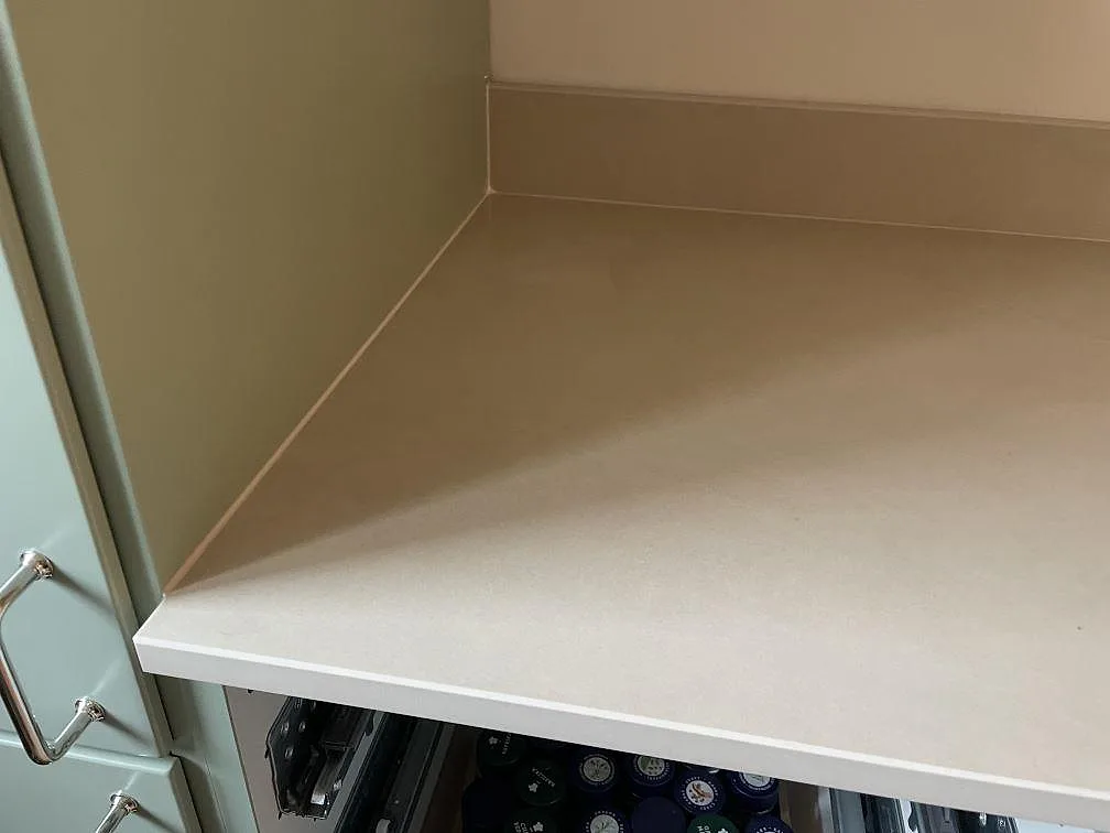 Rak bänkskivedel i matt Dekton Sasea keramik vid sagegröna köksluckor och stänkkant i ett kök i Malmö.
