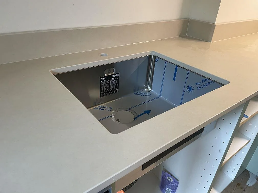 Närbild på underlimmad rostfri diskho i 20 mm matt Dekton Sasea keramik med uppvikt stänkkant i ett kök i Malmö.
