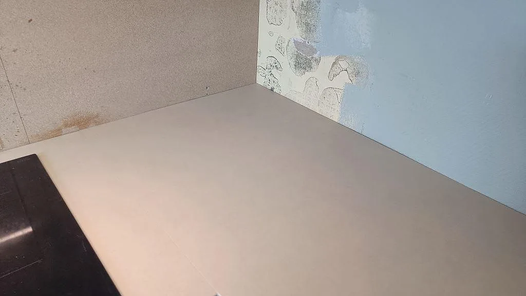 Närbild av ljus matt Dekton Sasea köksbänkskiva mot oavslutad köksvägg i Malmö.