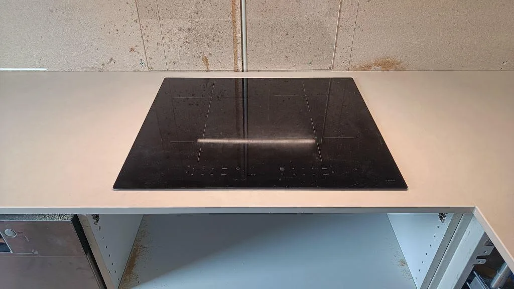 Svart häll monterad i en ljus matt köksbänkskiva av Dekton Sasea i ett kök i Malmö.