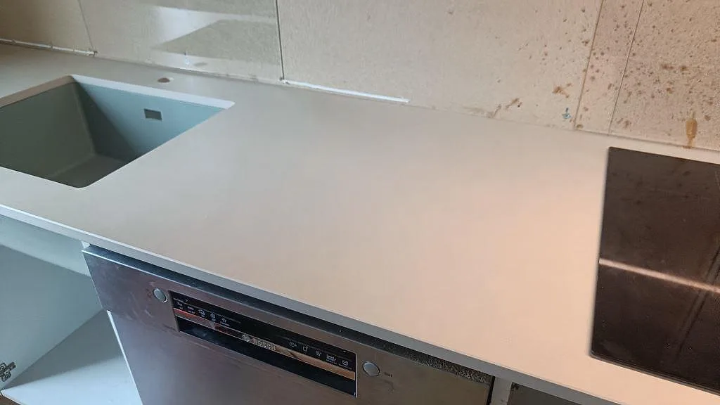 Matt Dekton Sasea köksbänkskiva med ljus taupe yta mellan underlimmad diskho och svart häll i Malmö.