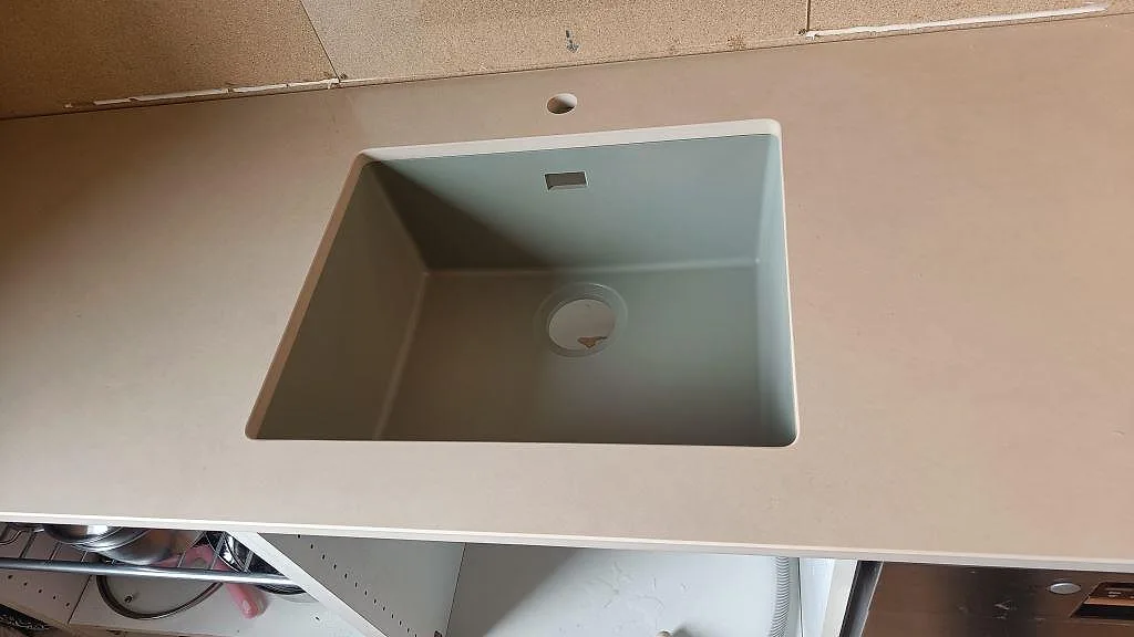 Underlimmad diskho i en matt Dekton Sasea köksbänkskiva, keramik, under montering i ett kök i Malmö.