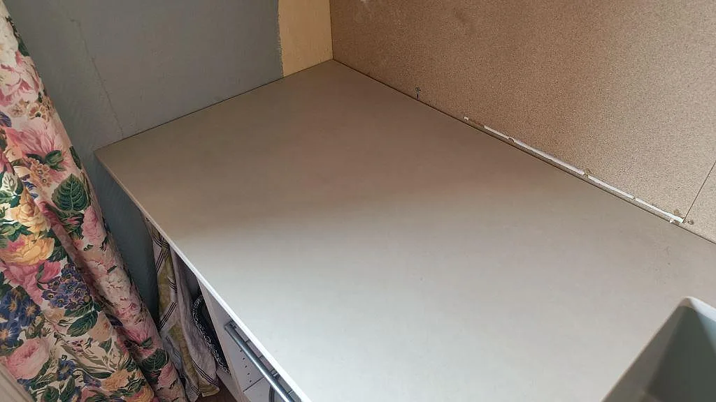 Köksbänkskiva i matt Dekton Sasea längs vägg och fönster under montering i Malmö.