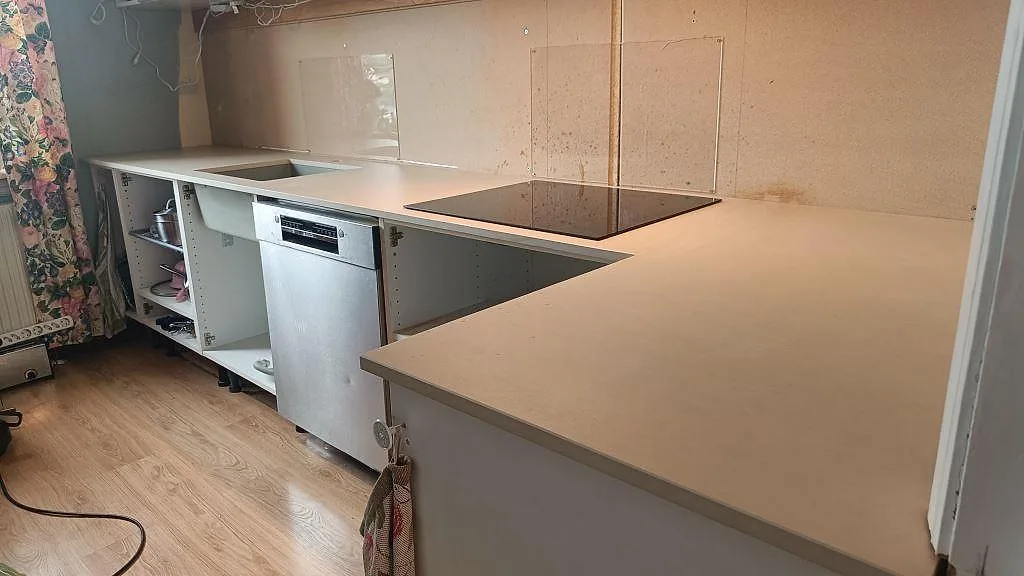 Köksbänkskiva i matt Dekton Sasea, keramik, med svart häll och underlimmad diskho på vita stommar i Malmö.
