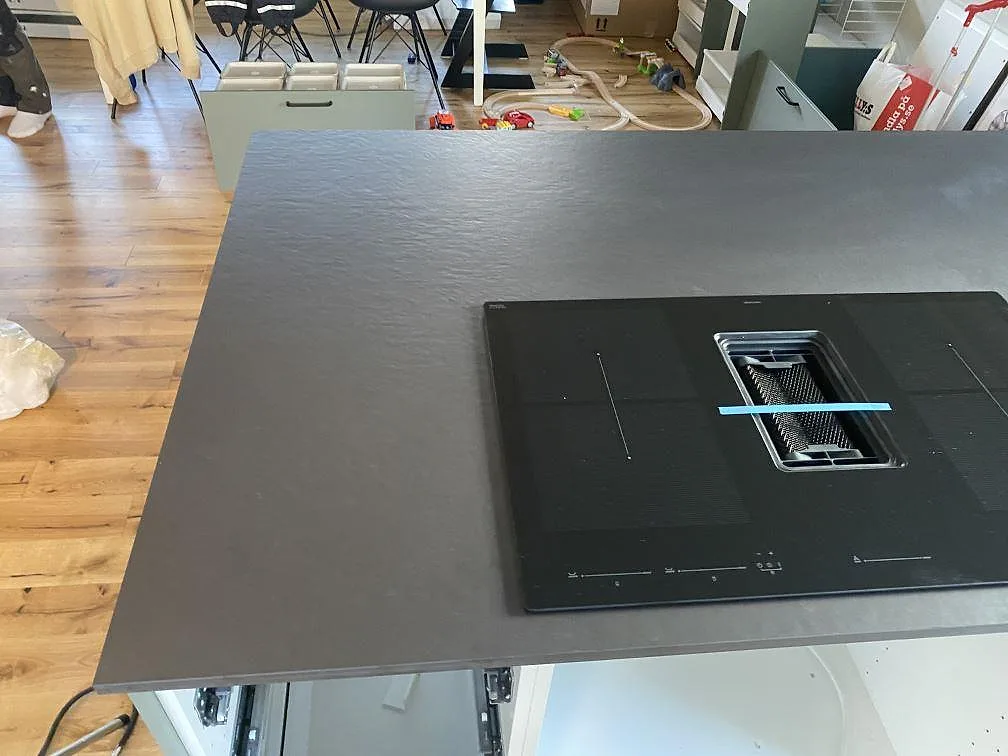 Köksö i mörk Dekton Sirius, matt, med induktionshäll sedd ovanifrån i ett kök i Ängelholm.